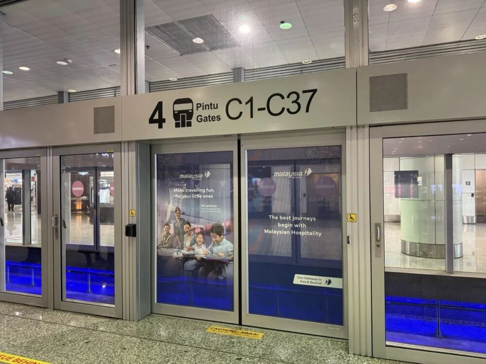 Aerotrain乗り場の自動ドア、Pintu Gates C1-C37と表示、マレーシア航空の家族向け広告