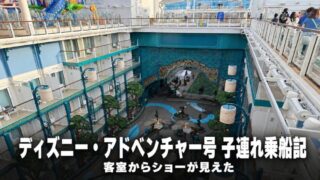 ディズニー・アドベンチャー号の船内庭園を上から見下ろした様子。左手に内向きバルコニーの客室が段状に並び、右手は乗客が見下ろす通路と舞台照明、奥に装飾アーチが見える