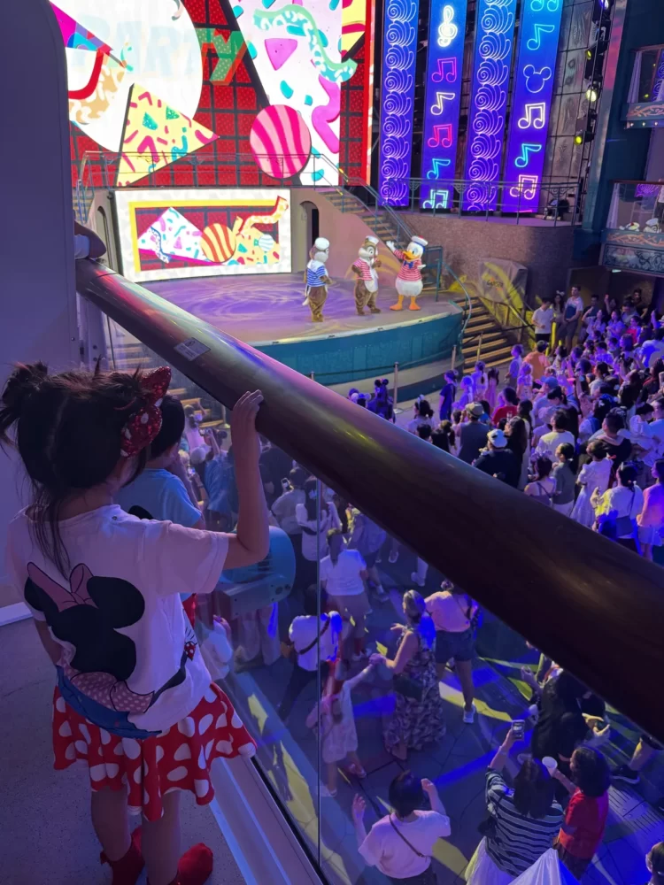 ガーデンステージでキャラクターと踊る夜のダンスパーティ。手すりから娘が見下ろしている