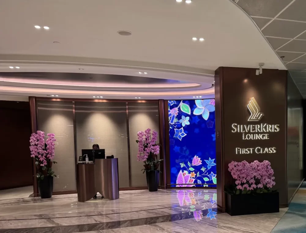 チャンギ空港T2 シルバークリスラウンジ ファーストクラスの入口。ゴールドのロゴサインと蘭の花が並ぶ