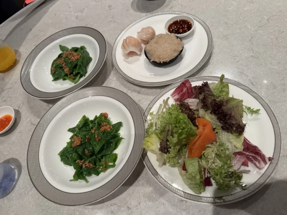実食プレート。海老の蒸し餃子などの点心、ガーリックソースの青菜、スモークサーモンのサラダ