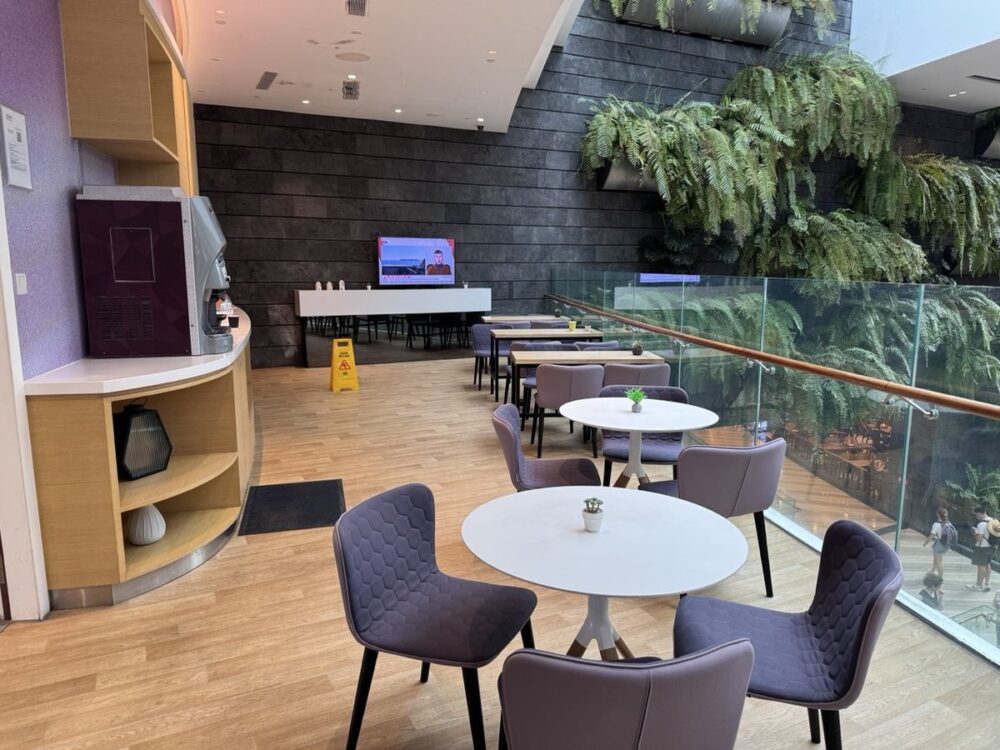 YOTELAIRのKomyunitiラウンジ。壁面のグリーンと白いテーブル席、コーヒーマシン