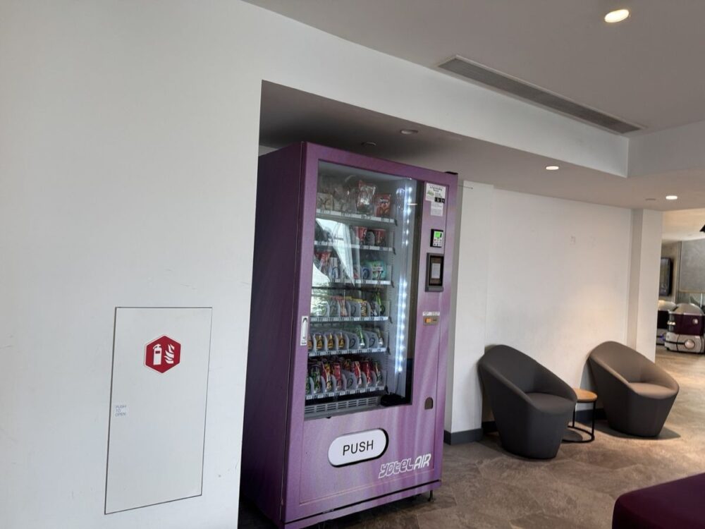 YOTELAIRカラーの紫色の自動販売機。スナックや飲み物が並ぶ