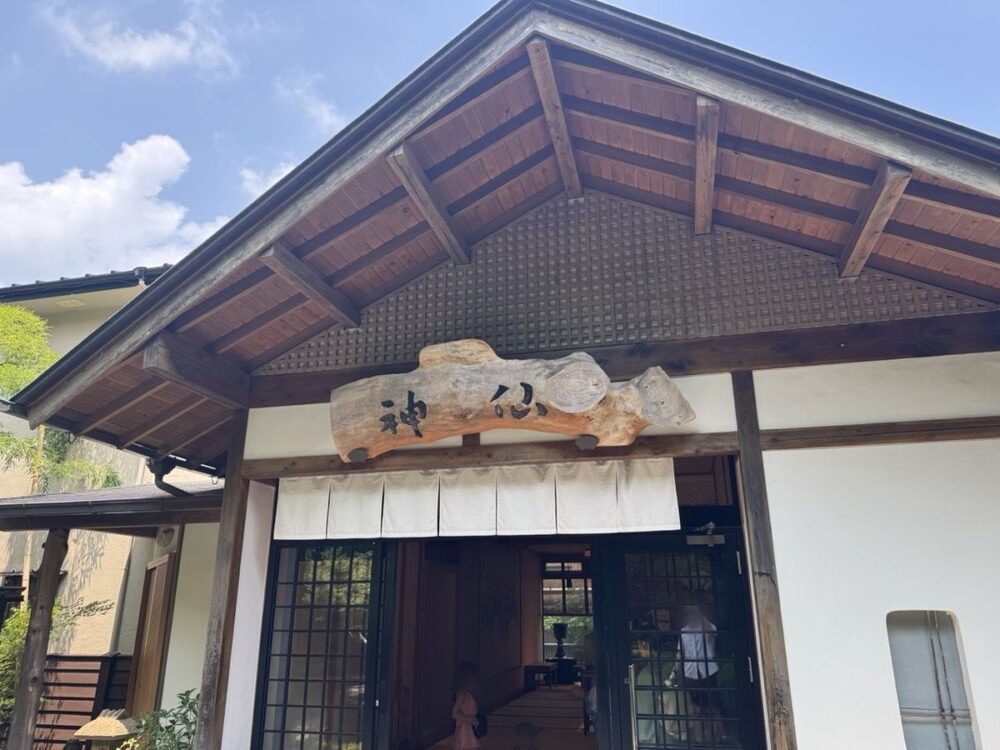 一枚板の看板と暖簾が掛かる旅館 神仙の玄関